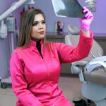 une femme assise sur une chaise de dentiste tenant un miroir