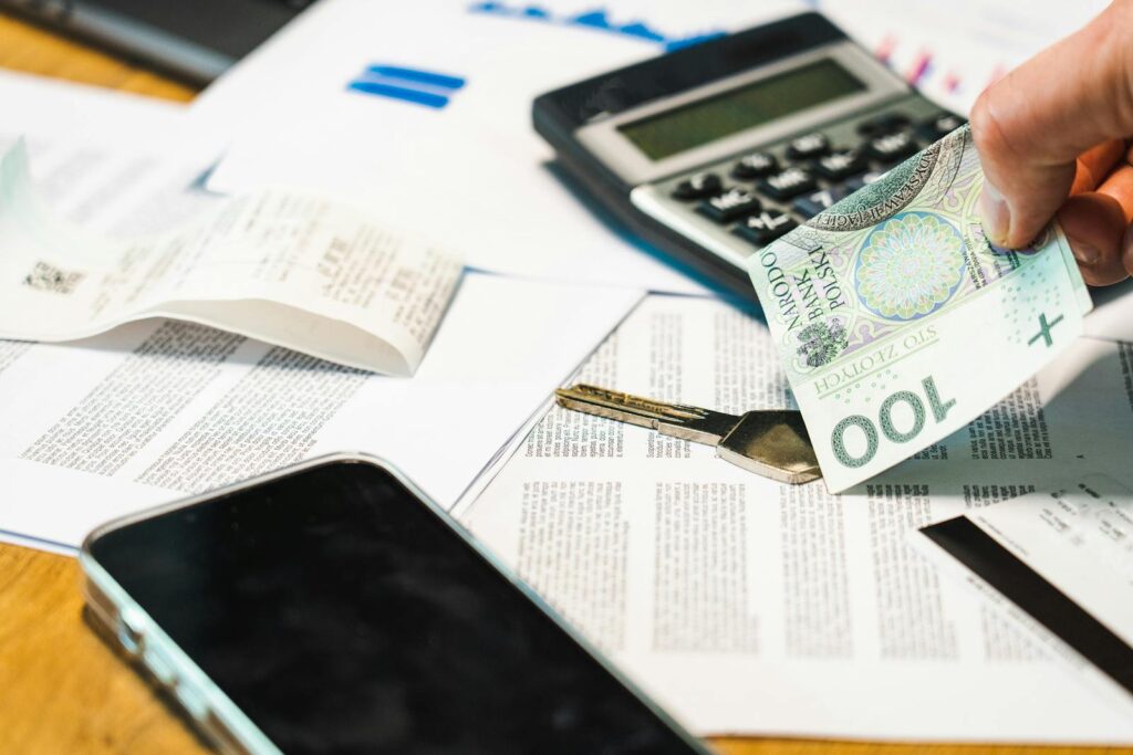 Gros plan de documents financiers, d'une calculatrice et de la monnaie zloty polonaise sur un bureau.