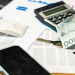 Gros plan de documents financiers, d'une calculatrice et de la monnaie zloty polonaise sur un bureau.