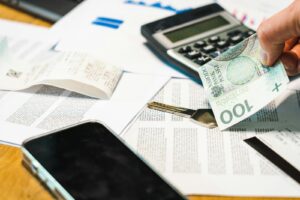 Gros plan de documents financiers, d'une calculatrice et de la monnaie zloty polonaise sur un bureau.