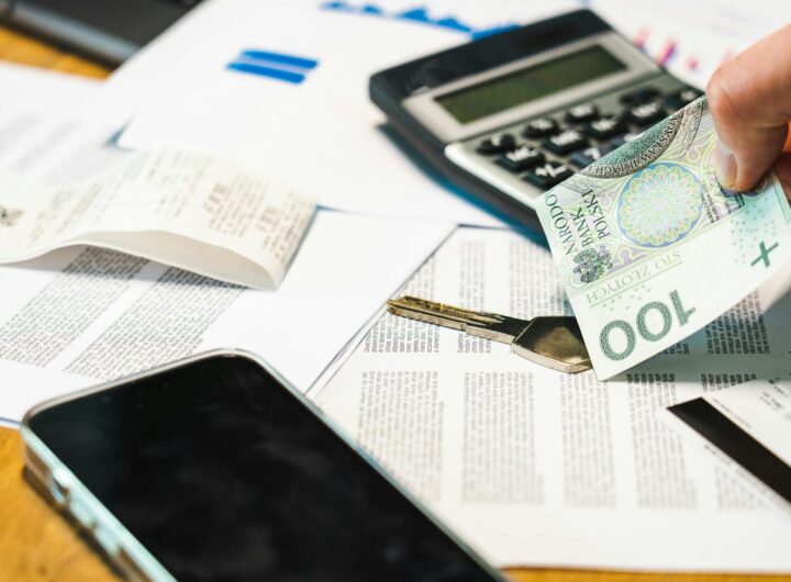 Gros plan de documents financiers, d'une calculatrice et de la monnaie zloty polonaise sur un bureau.