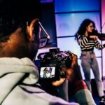 a woman holding a camera in front of a man