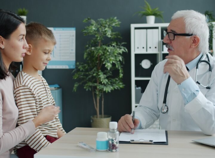 Doctor talking to mother and child at desk.