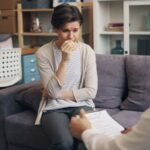 a woman sitting on a couch talking to a man