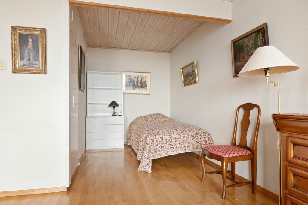 A bedroom with a bed and a chair in it