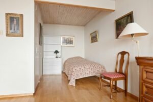 A bedroom with a bed and a chair in it