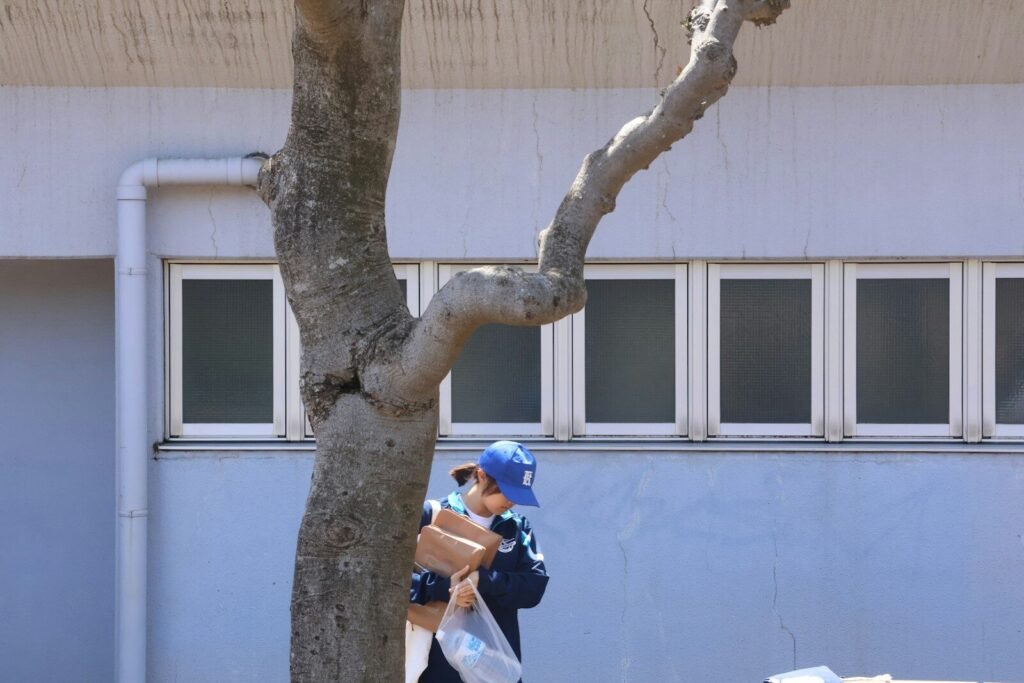 A child walks carrying packages near a building.