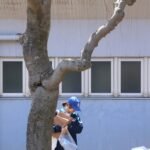 A child walks carrying packages near a building.