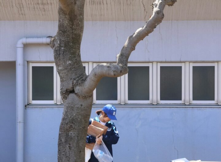 A child walks carrying packages near a building.