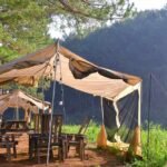 Tentes de moustiquaire avec tables et chaises en bois, lieu de camping en forêt
