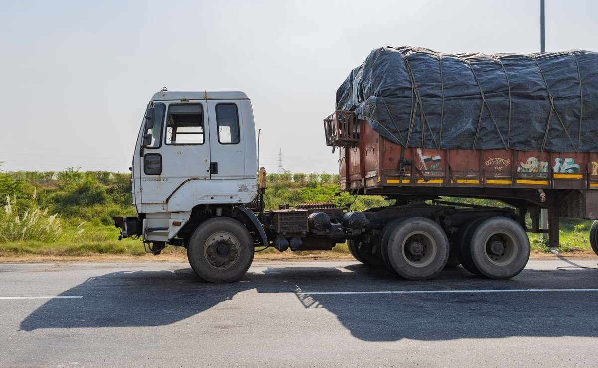 Camion blanc tracte une remorque couverte sur une route Camion blanc tracte une remorque couverte sur une route
