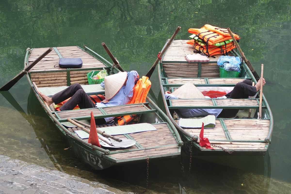 Deux personnes reposent dans des bateaux en bois sur l'eau