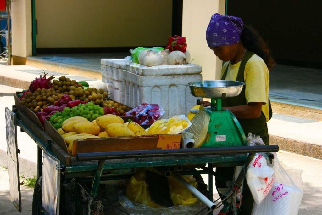 Vendeuse pesant des fruits et légumes sur un chariot de marché