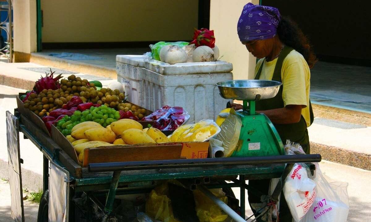 Vendeuse pesant des fruits et légumes sur un chariot de marché