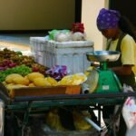 Vendeuse pesant des fruits et légumes sur un chariot de marché