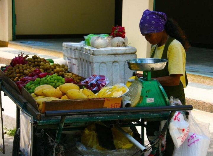 Vendeuse pesant des fruits et légumes sur un chariot de marché