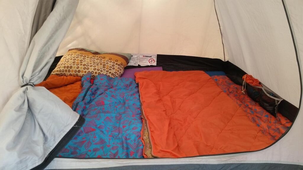 L'intérieur d'une tente avec coussin, couvertures et sac de couchage