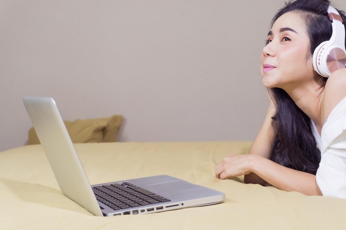 Une femme écoute de la musique via casque tout en regardant son ordinateur